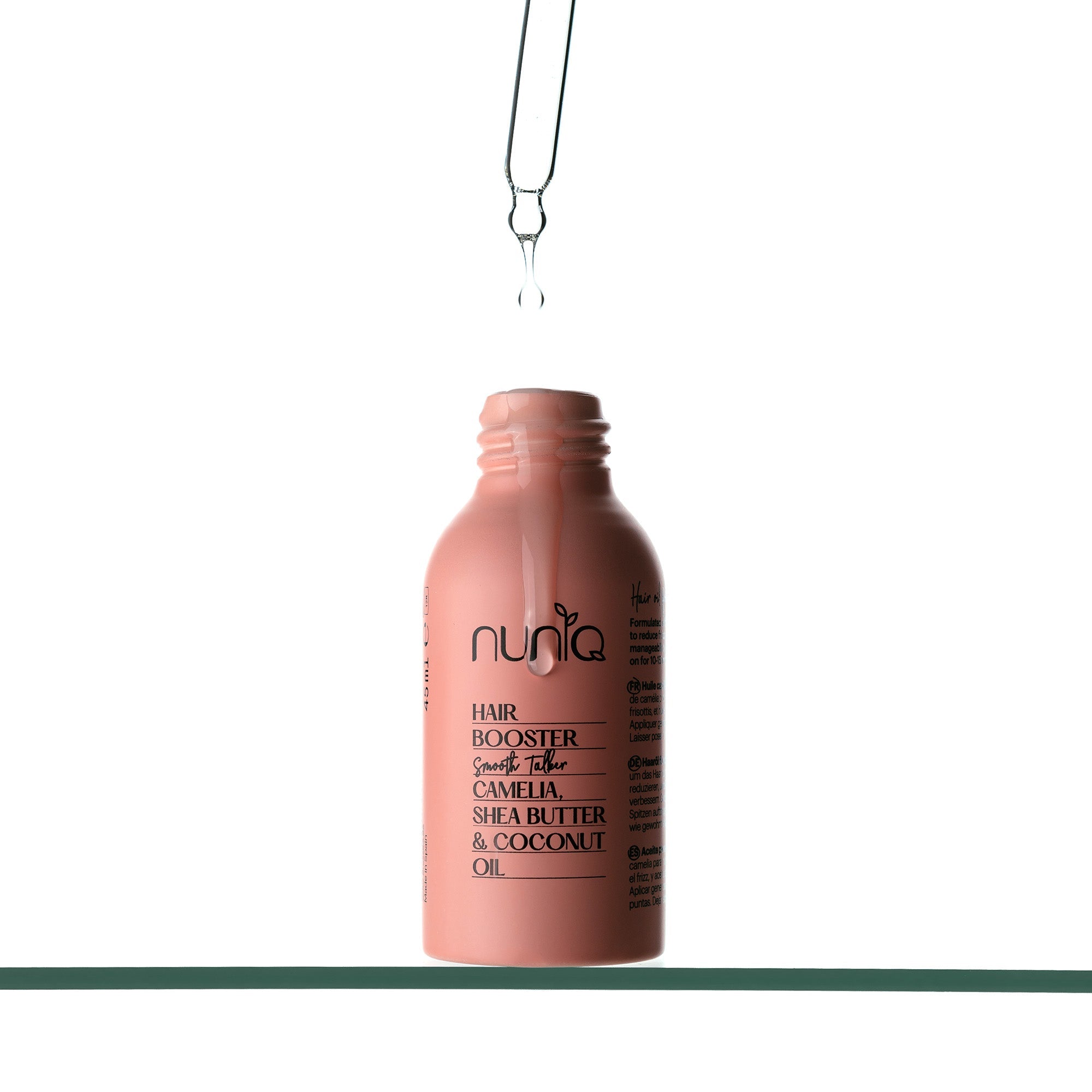 Close-up of the Nuniq Smooth Talker hair oil bottle for frizz control and nourishment.