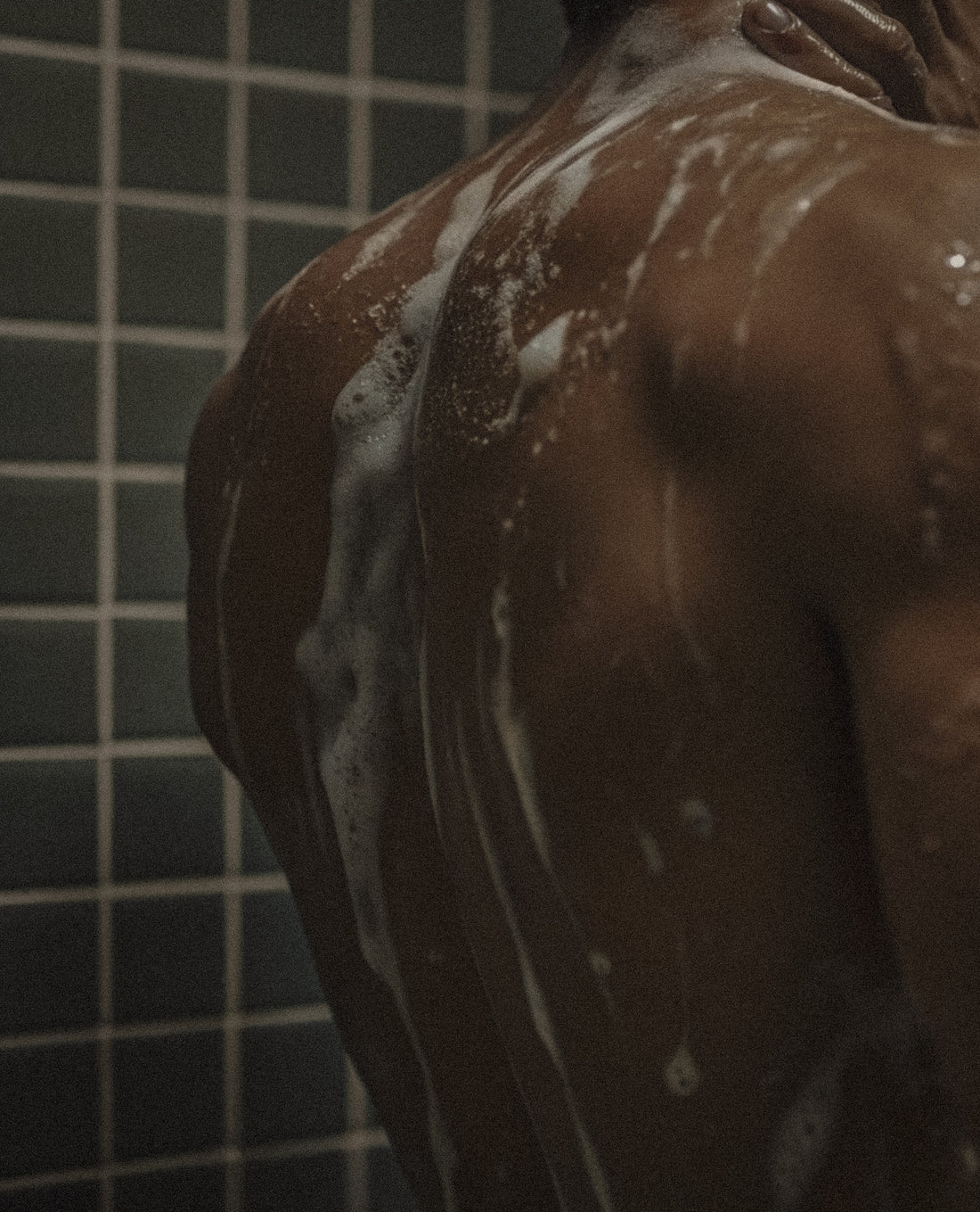 Person with soapy shoulders and arms in a bathroom setting